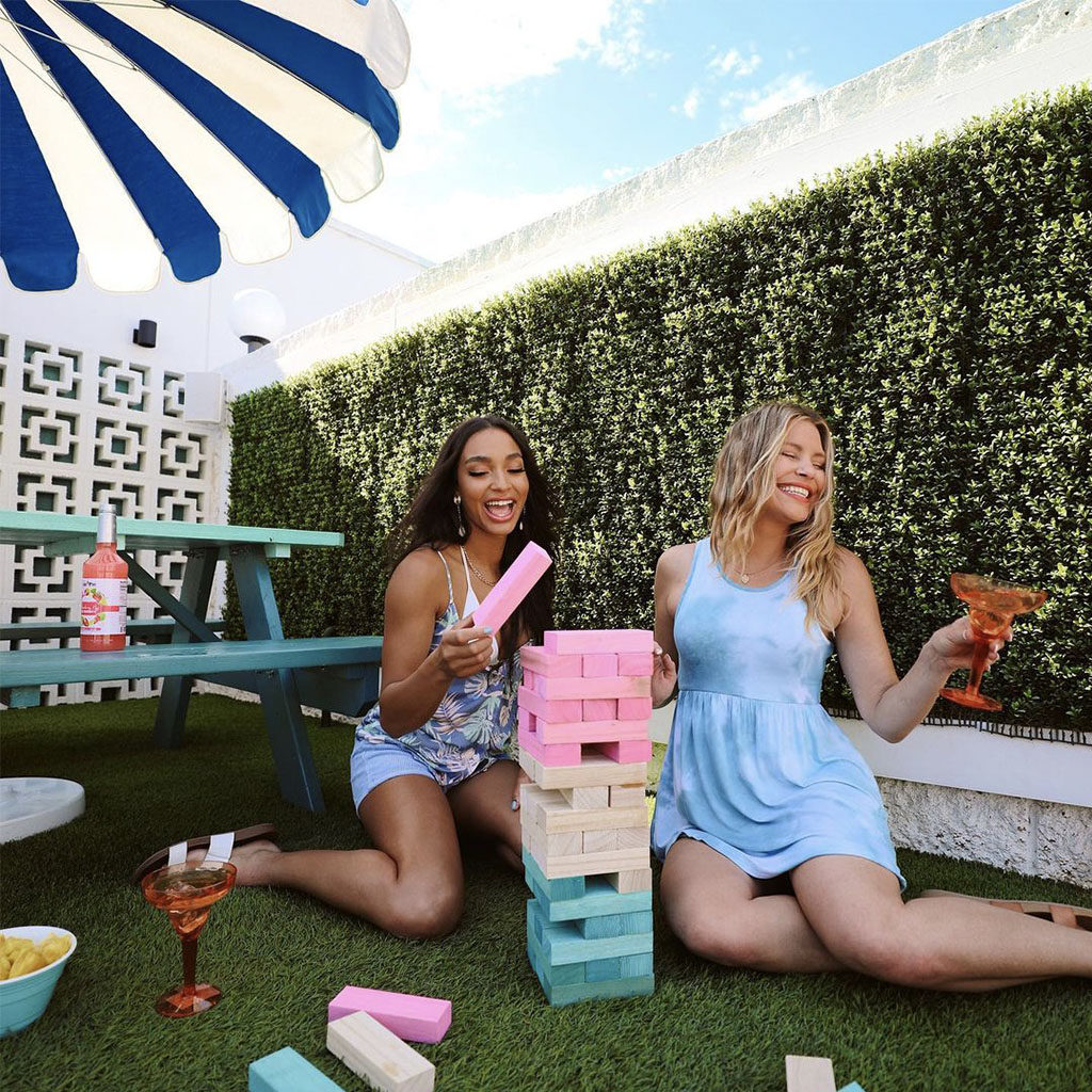 Two girls playing giant Jenga in the picnic area of the pool at The Rambler Motel