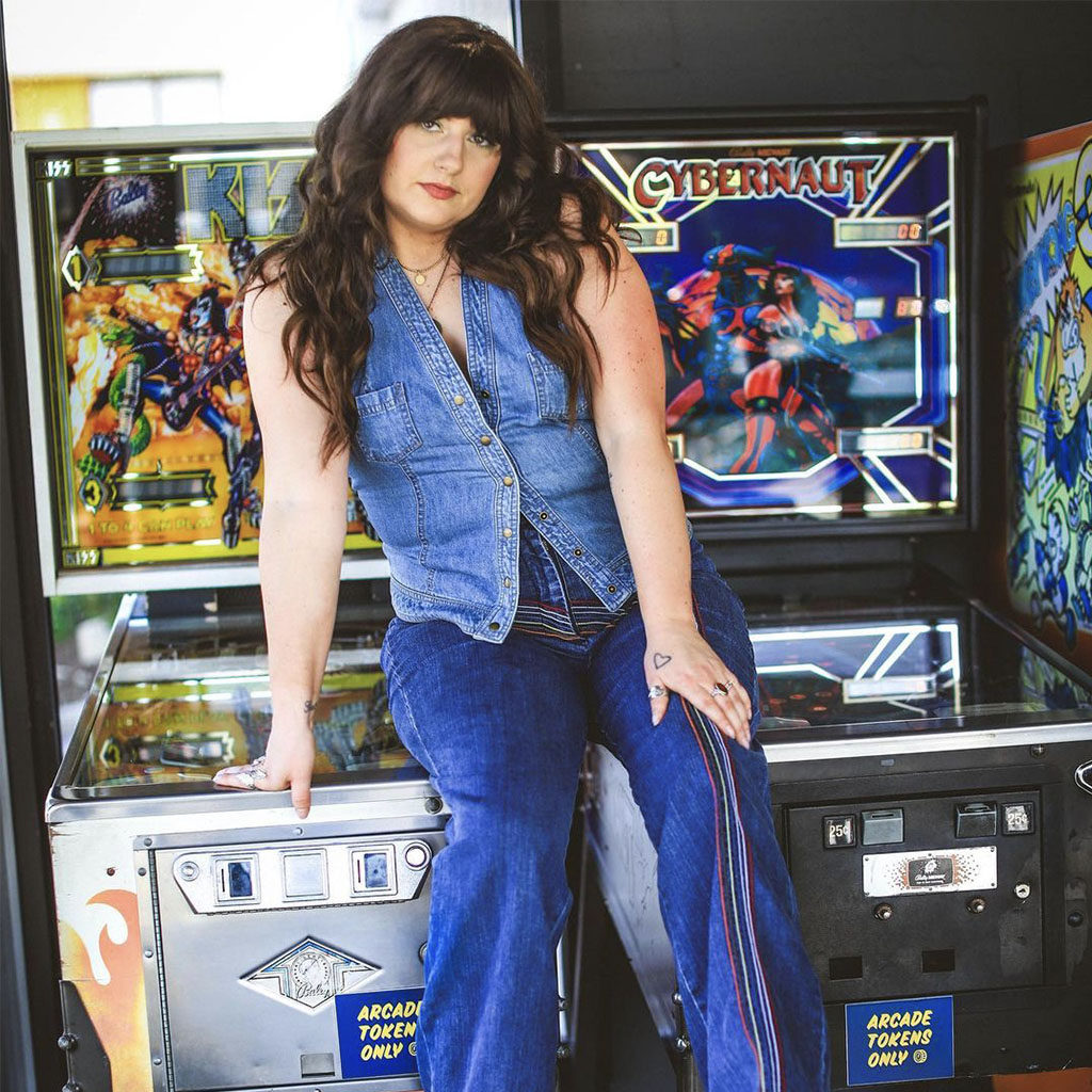 Woman in denim on denim sitting on the arcade games at The Rambler Motel