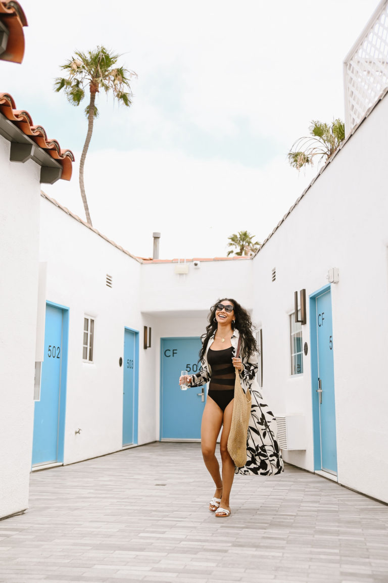 Woman walking through the white hallway with blue doors at Bellanca Hotel