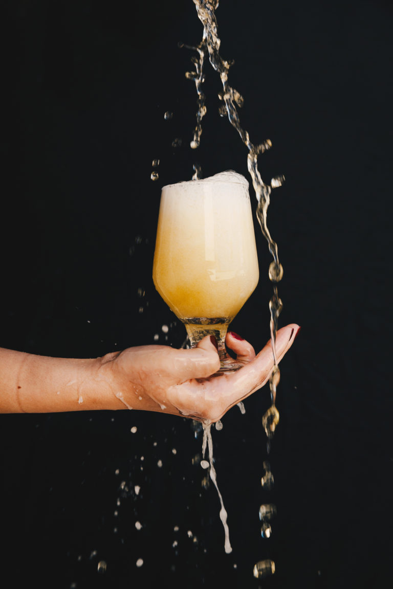 Hand holding a chalice of beer slashing on a black background