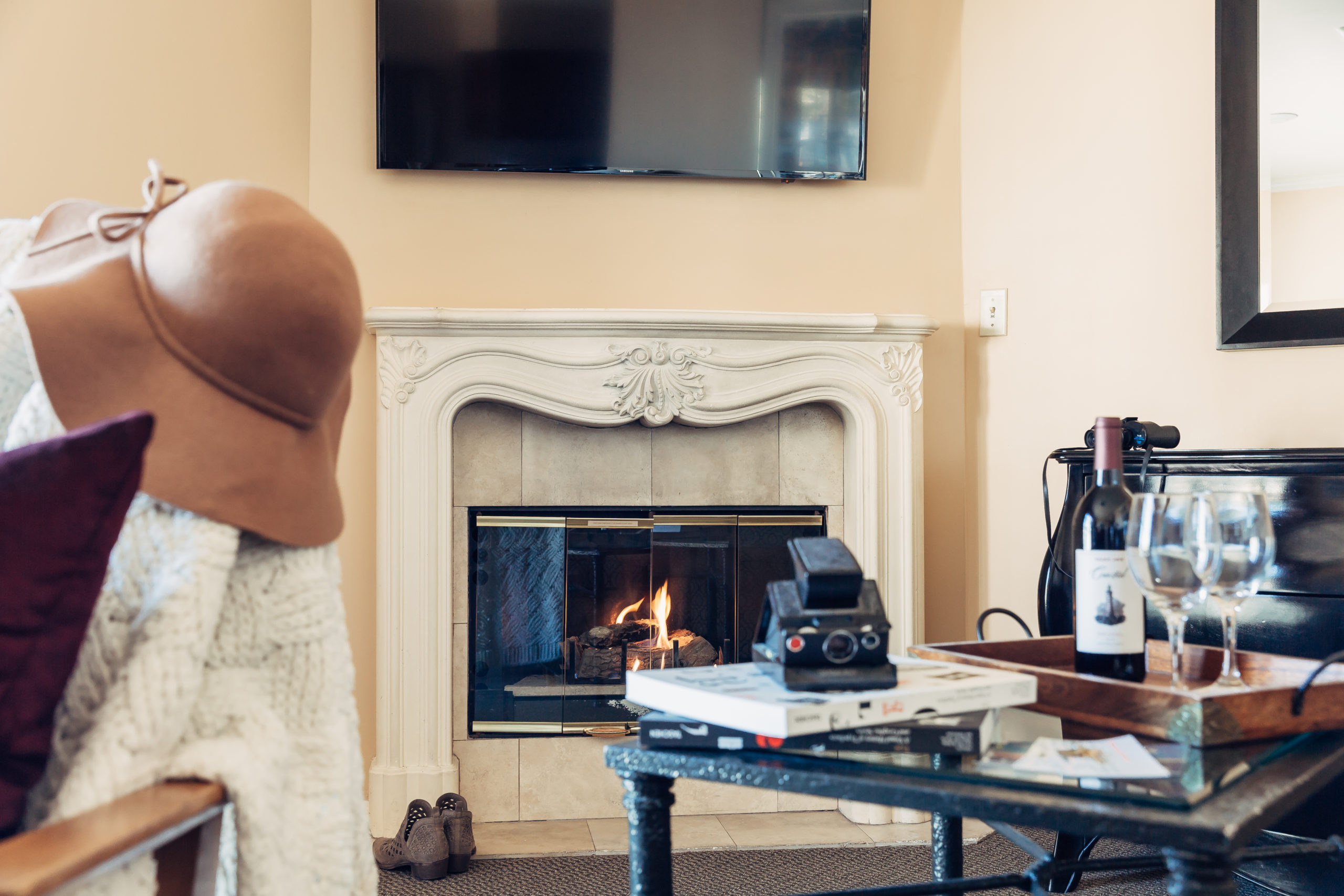 Guestroom fireplace styled with wine and polaroid camera