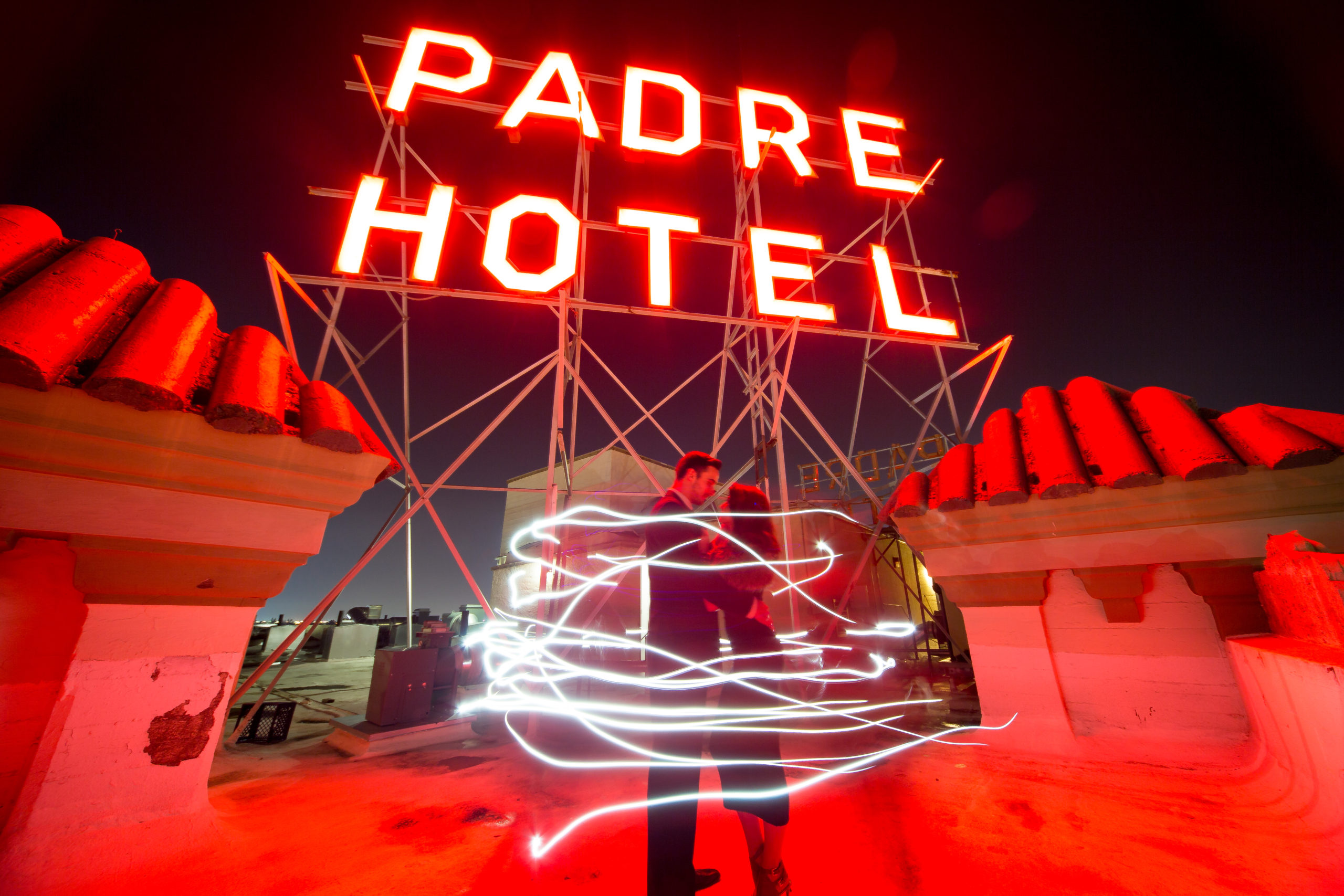 Rooftop Padre Hotel sign lit up in a red with couple standing in front of it