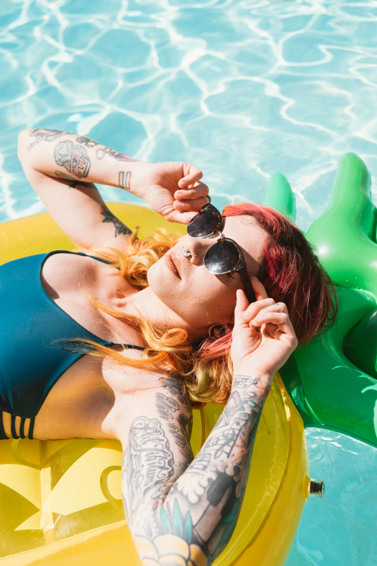 Woman laying on a pineapple floatie in the pool with sunglasses on